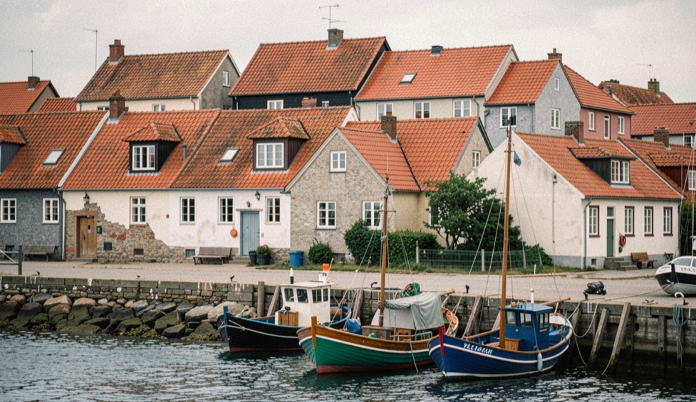 Red pantile roofs of a fishing village stacked above a small harbour with fishing cobles drawn up on the slipway